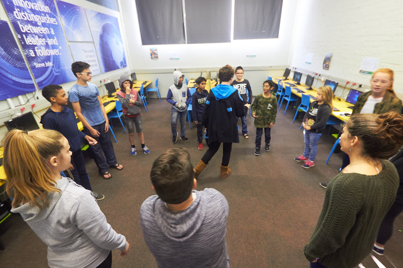 A circle of campers and instructors mid-activity in the computer lab at one of the first Think Camps, 2018.